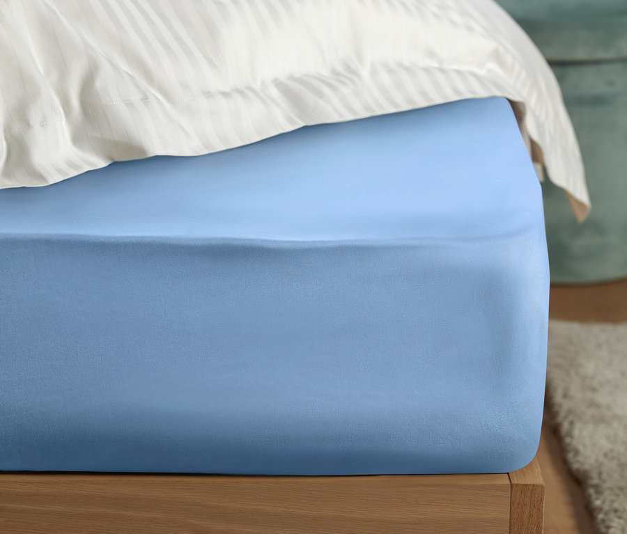 Detailansicht eines Bettes mit einem hellblauen Perkal-Spannbettlaken.