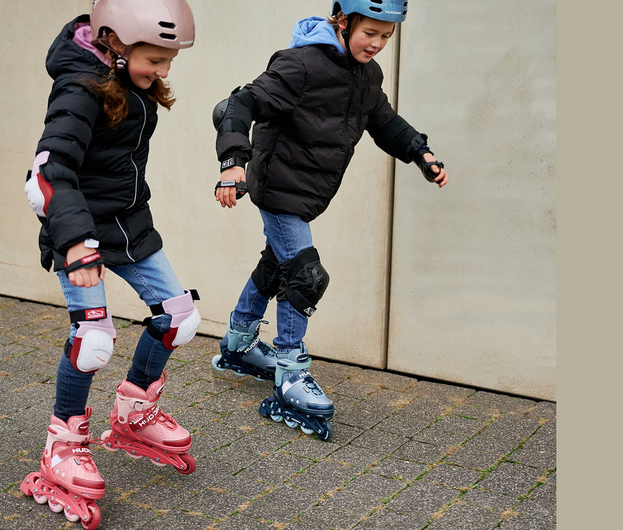 Zwei Kinder fahren mit HUDORA Inline Skates »Leon 2.0« und Schutzausrüstung.