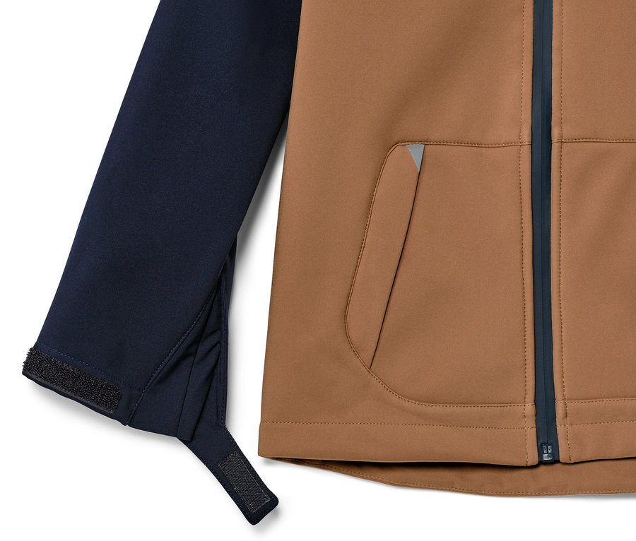 Detailansicht einer Kinder-Softshelljacke mit brauner Vorderseite und dunkelblauem Ärmel.