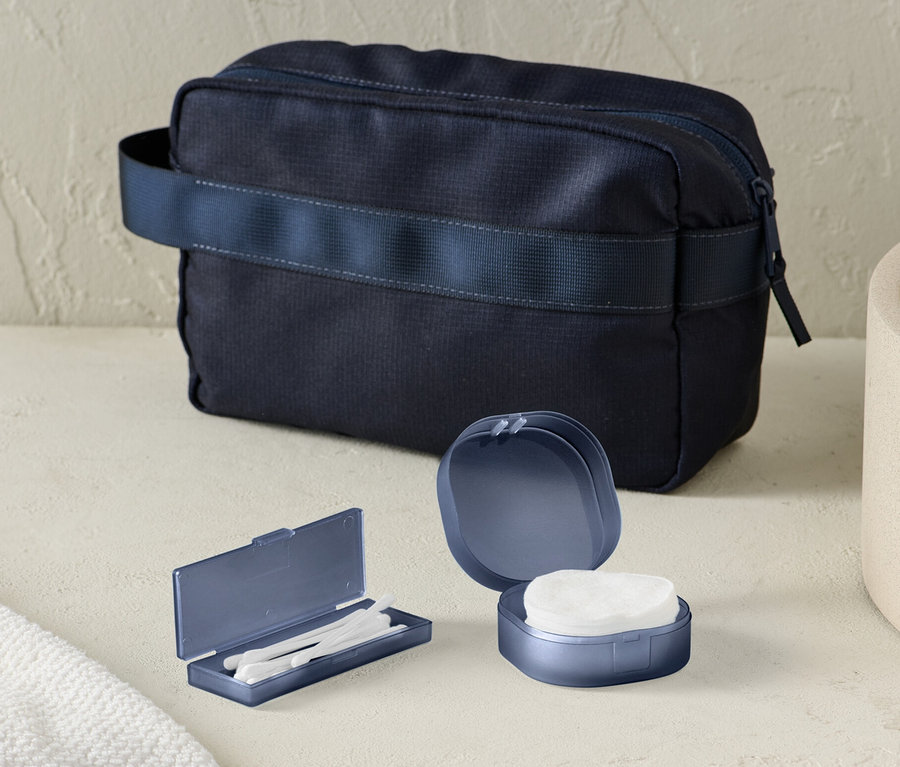 Auf dem Tisch liegen ein Aufbewahrungs-Set und eine dunkelblaue Kulturtasche.