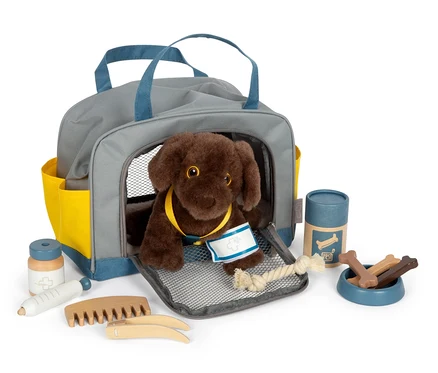 Brauner Plüschhund in grauer small foot Tasche mit blauen Details und gelben Taschen, zusammen mit medizinischem Zubehör.