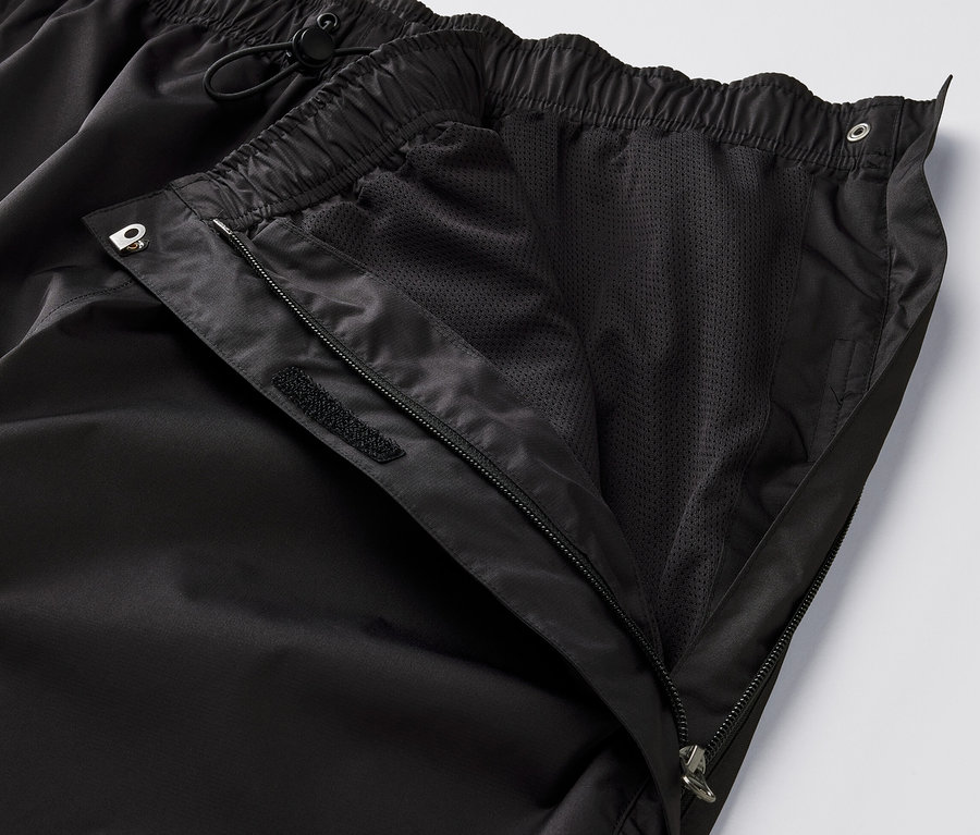 Detailaufnahme einer schwarzen High-Tech-Regenhose, deren Reißverschluss geöffnet ist und das Netzfutter sichtbar macht.