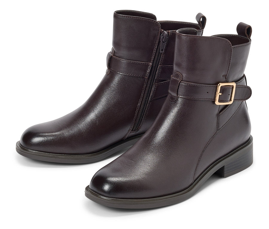 Zwei braune Stiefeletten mit Schnalle und Reißverschluss liegen auf einem weißen Hintergrund.