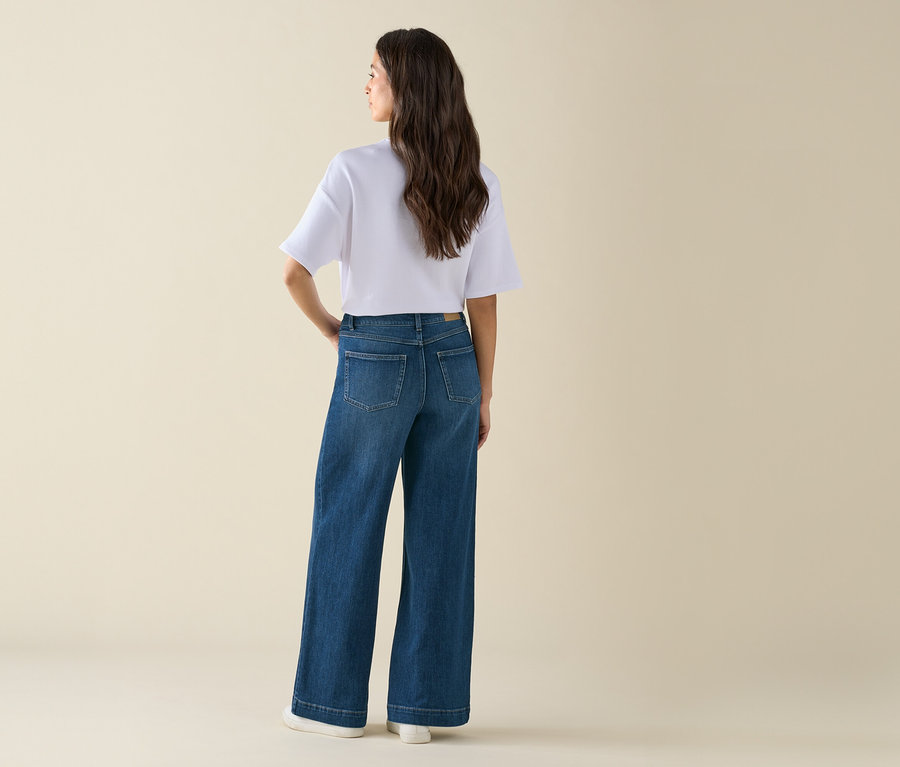 Frau posiert in einer weiten Jeans und einem weißen T-Shirt.