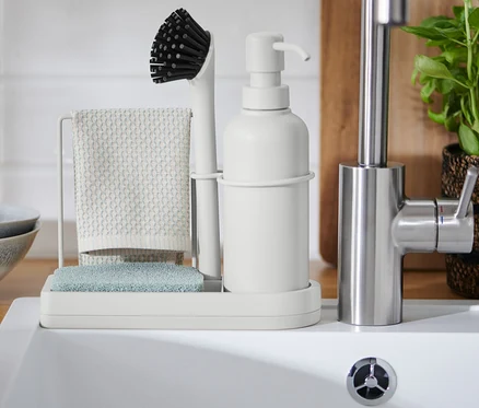 Spülbecken-Organizer mit Bürste, Lappen und Seifenspender neben Spülbecken.