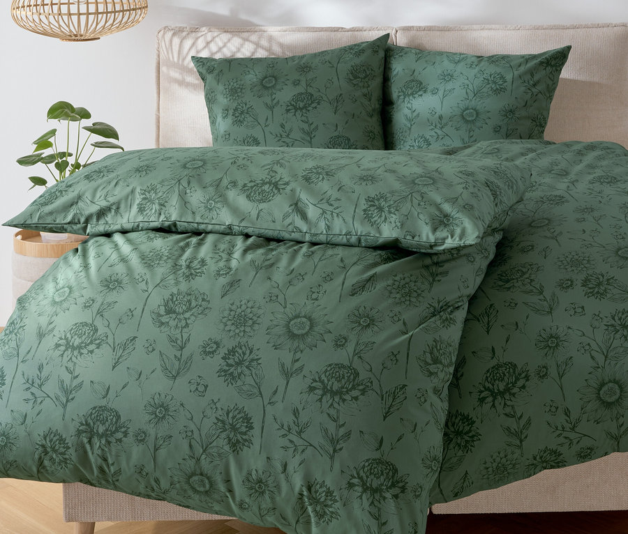 Grüne Bettwäsche mit Blumenmuster auf einem Bett.