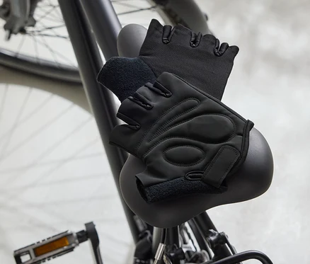 Zwei schwarze Fahrradhandschuhe liegen auf einem schwarzen Fahrradsattel.
