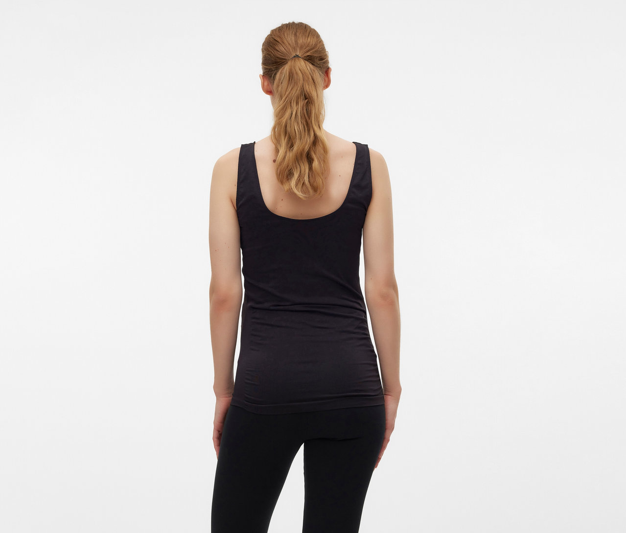 Rückansicht einer Frau mit blondem Haar im Pferdeschwanz, die ein schwarzes MAMALICIOUS Tanktop »MLHEAL« in Einheitsgröße trägt.