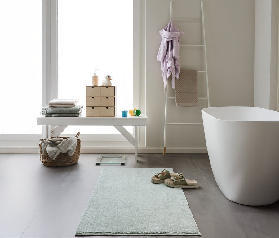 Badezimmer mit weißer Bank, Badewanne und mintfarbener benuta Badematte »Ole« 50 x 80 cm.