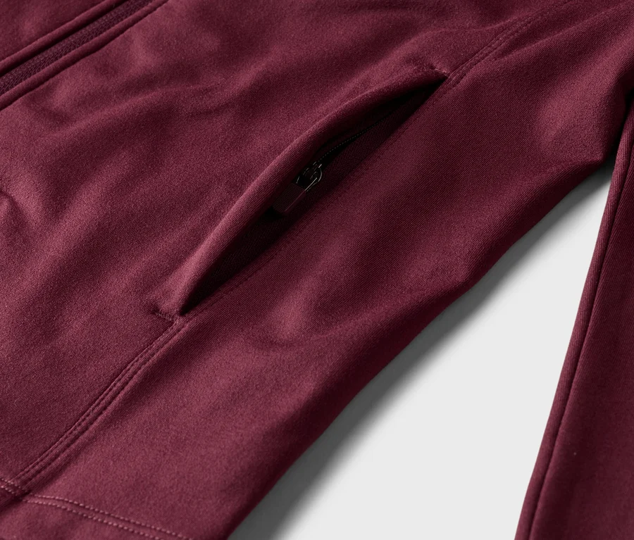 Nahaufnahme einer burgunderroten Jacke mit Reißverschluss und Seitentasche.