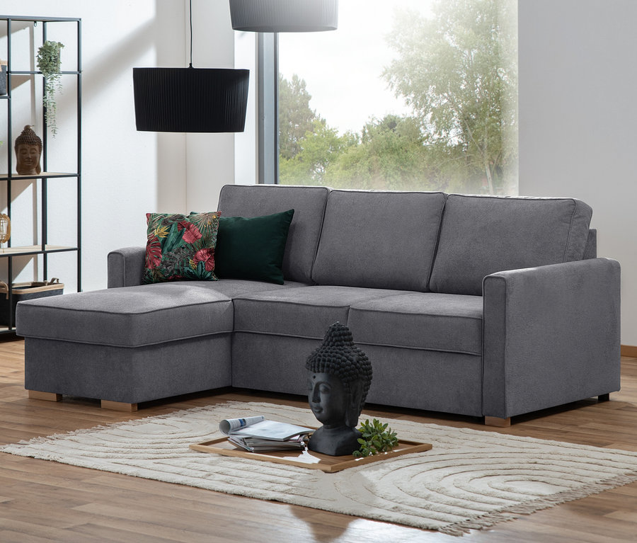 Graues Ecksofa mit Auszugsbett »NovaLounge« mit Kissen steht auf einem gemusterten Teppich.