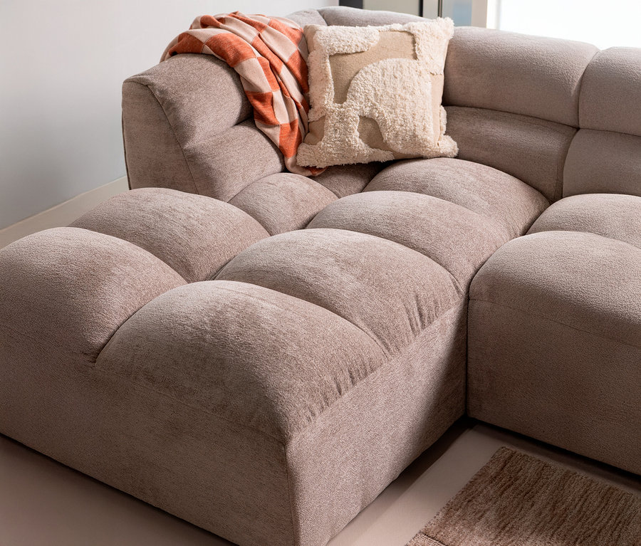 Detailansicht eines modularen Sofas in Beige mit einer orange-weiß karierten Decke und einem beigen Kissen.