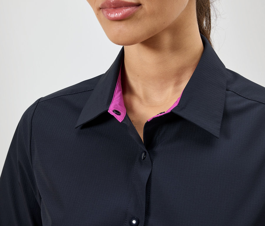 Nahaufnahme einer Frau, die ein dunkelblaues Hemd mit pinkfarbenem Kragen trägt.