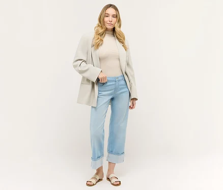Frau in hellblauer Angels Denim »Laia Turn-Up« Wide Leg Jeans mit hochgekrempeltem Bein, beigem Oberteil und Blazer.