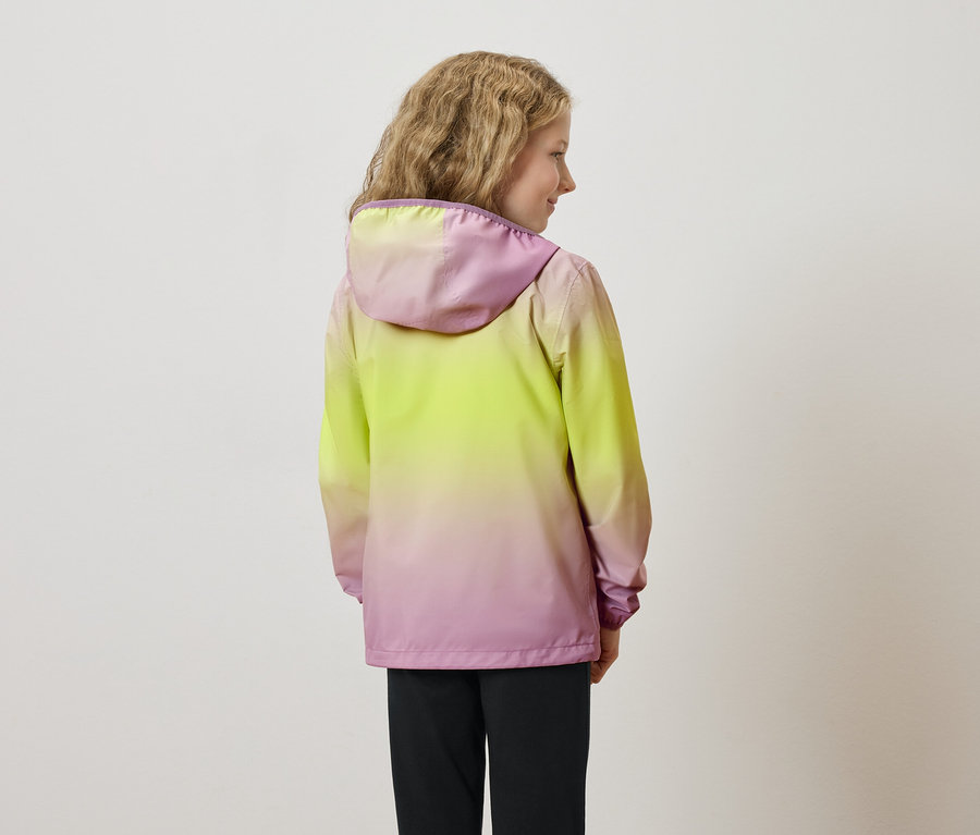 Rückansicht eines jungen Mädchens mit gewelltem Haar, das eine gelb-rosa Jacke mit Kapuze und eine schwarze Hose trägt.