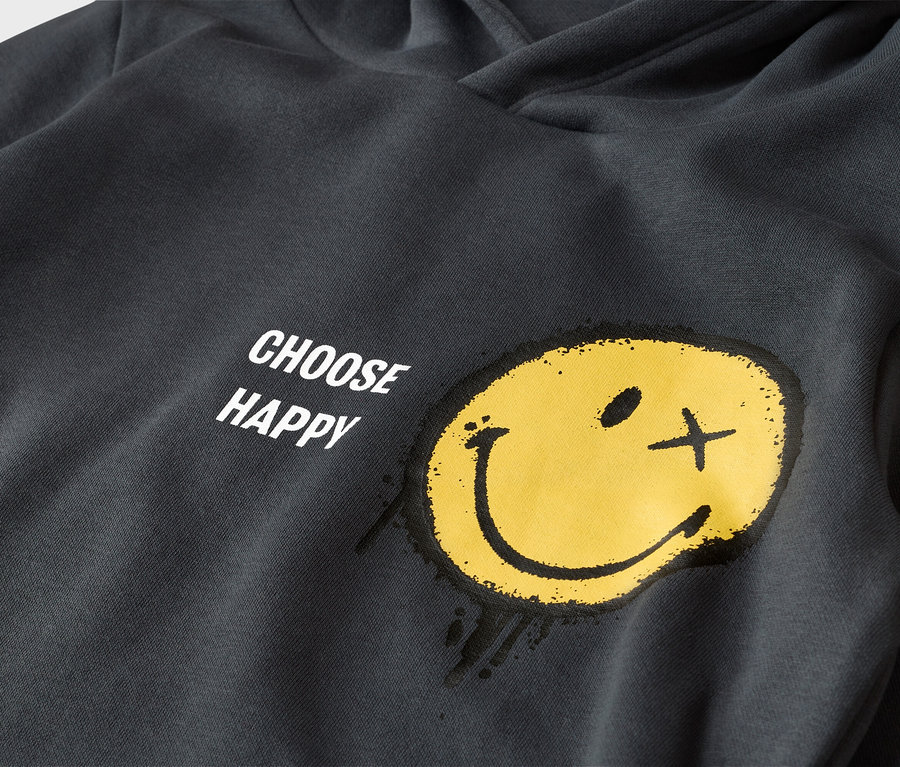 Dunkelgrauer Hoodie mit gelbem Smiley-Gesicht und dem Schriftzug "CHOOSE HAPPY". Der Smiley hat ein Punktauge und ein Kreuzauge und wirkt wie aufgesprüht.