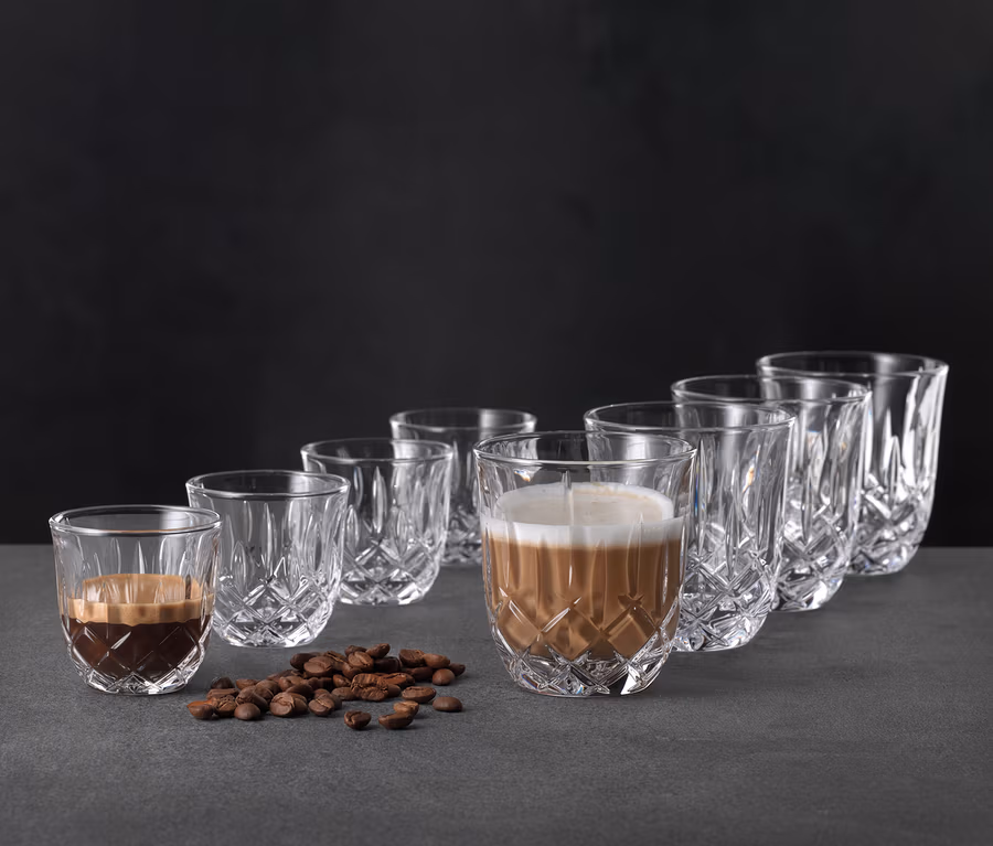Abbildung von sechs Nachtmann Cappuccinogläsern »Noblesse«, von denen zwei mit Kaffee gefüllt sind, zusammen mit Kaffeebohnen.