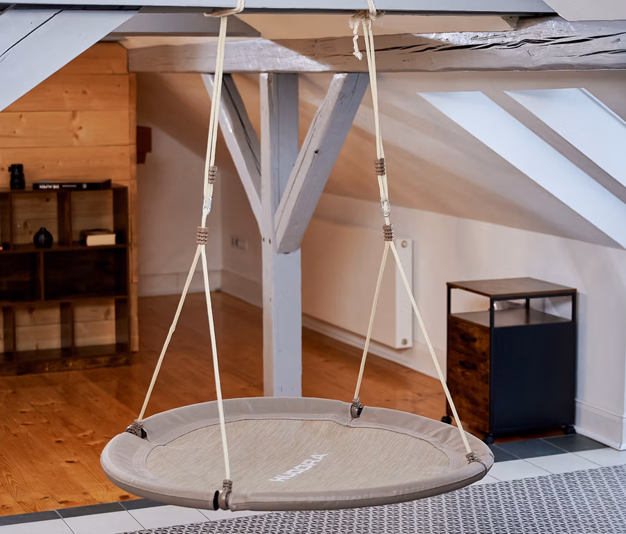 Eine beige HUDORA Nestschaukel »Lounge«, Ø 110 cm hängt von der Decke in einem Innenraum.