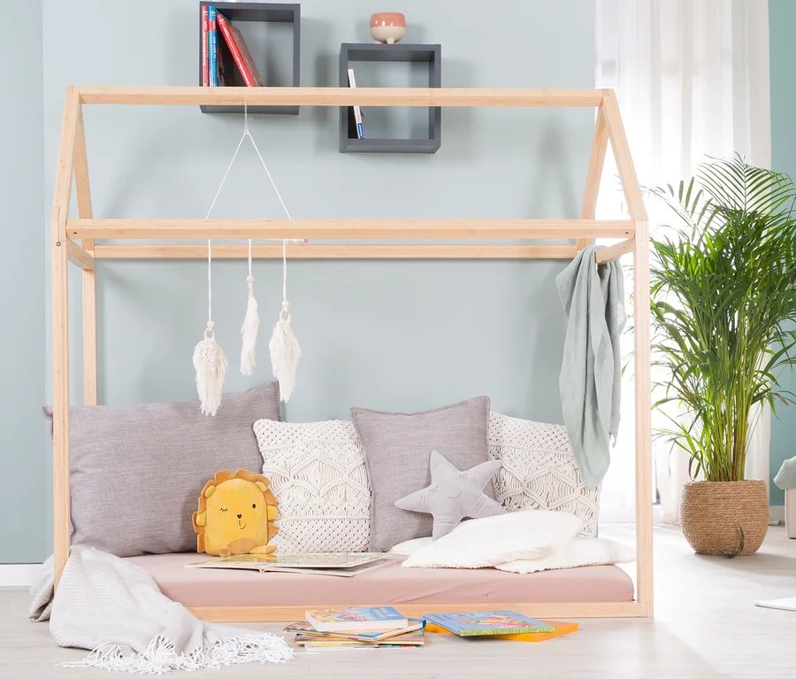 Ein roba Hausbett, ca. 70 x 140 cm, aus Bambus, umgeben von Kissen und Spielzeug.