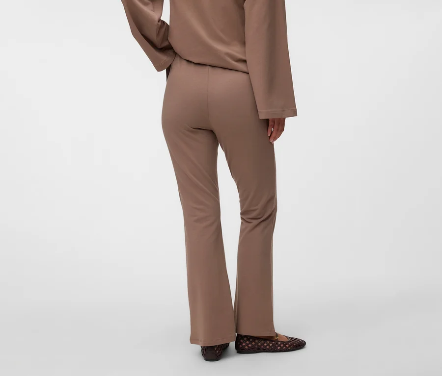 Person von hinten in braunem Langarmshirt und brauner, ausgestellter MAMALICIOUS Sweat Pants »MLSINE HW« mit dunkelbraunen, geflochtenen Ballerinas.