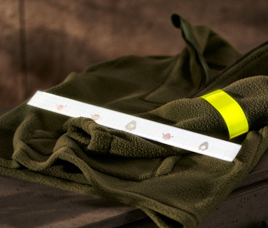 Auf einer olivgrünen Fleecejacke liegen 2 reflektierende Schnapp-Armbänder.