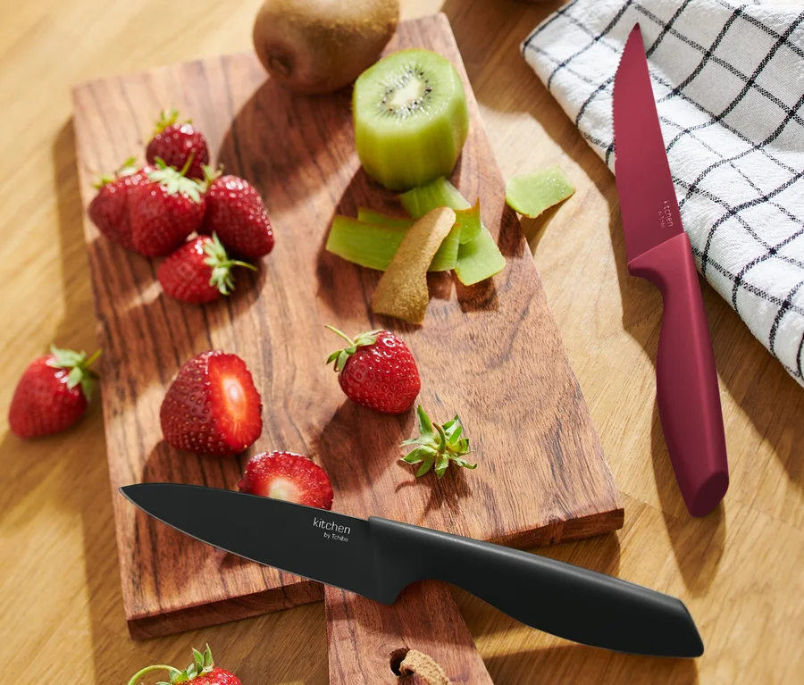 Erdbeeren und Kiwis auf einem Holzbrett mit zwei Küchenmessern.