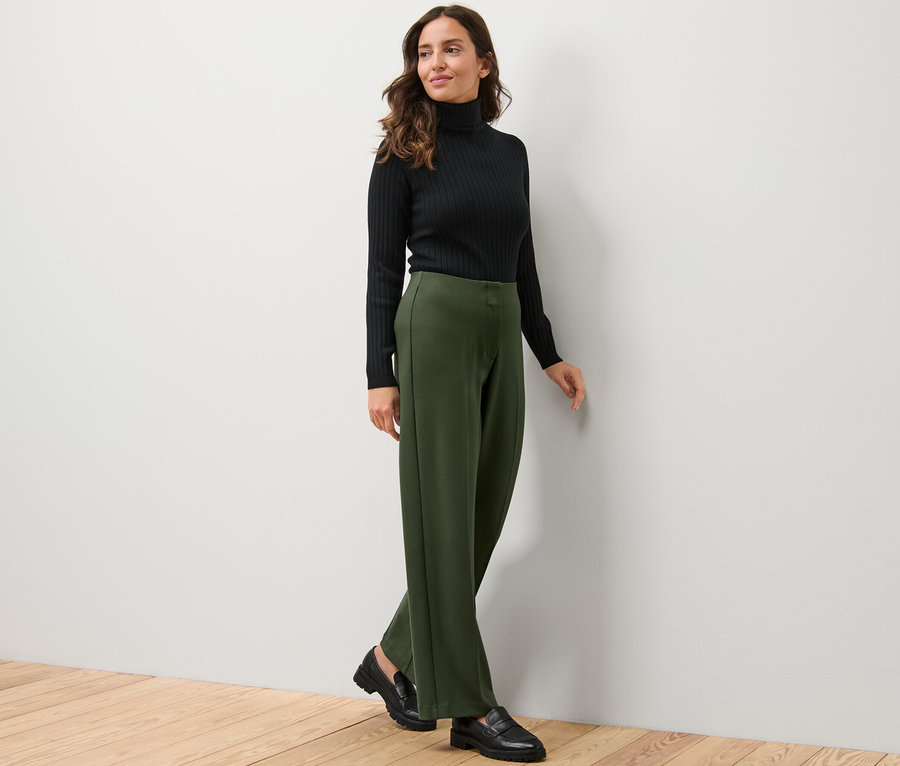 Frau trägt schwarzen Rollkragenpullover und Jerseyhose.