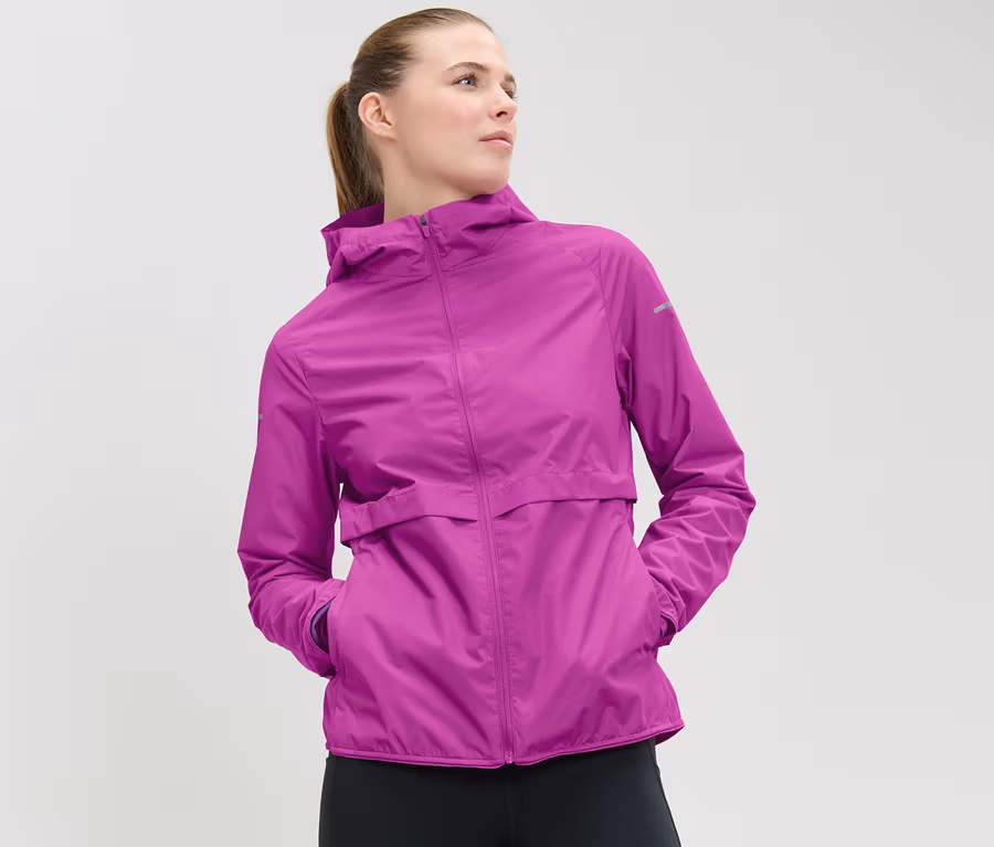 Frau trägt Windprotection-Laufjacke, neonbeere, und schwarze Leggings.