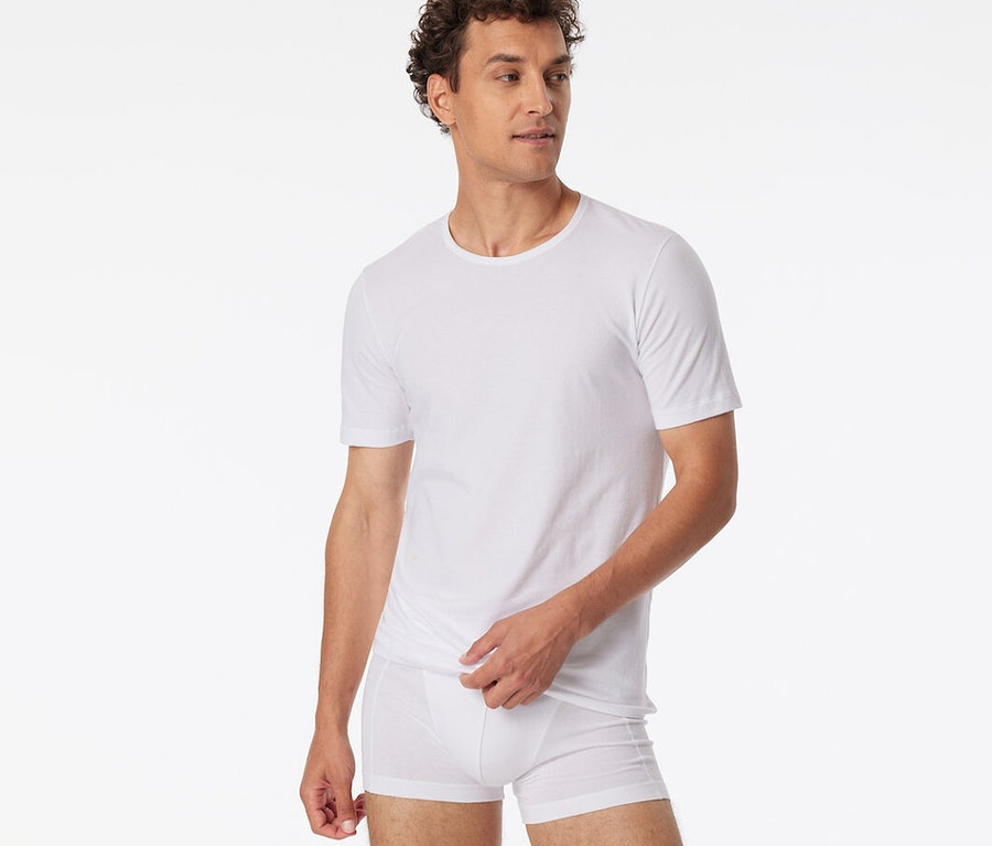 Mann trägt zwei weiße SCHIESSER T-Shirts mit Bio-Baumwolle.