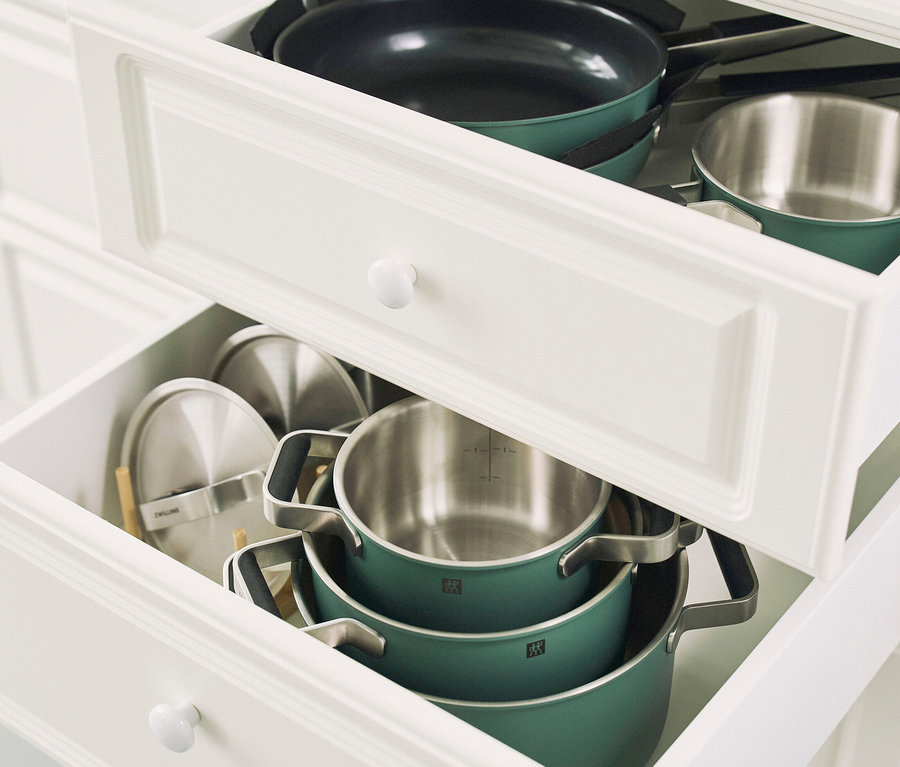 Geöffnete Schubladen in einem weißen Schrank enthalten ein grünes, 5-teiliges ZWILLING PURE Edelstahl-Kochgeschirr-Set.