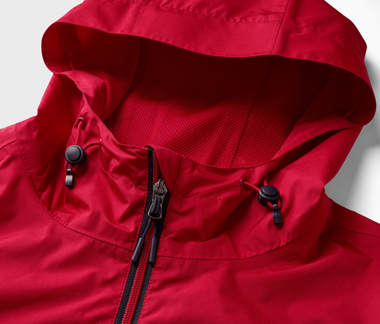 Detailaufnahme einer roten Regenjacke mit Reißverschluss und Kapuze.