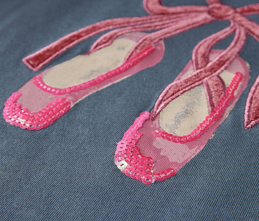 Detailaufnahme von rosa Ballettschuhen mit Schleife auf blauem Hintergrund.