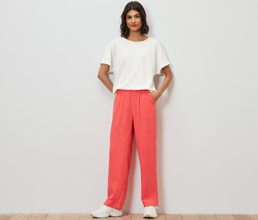 Frau steht mit Händen in den Taschen der Webhose.