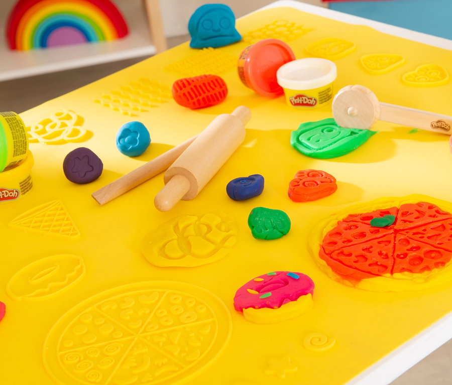 Gelbe Unterlage auf einem Tisch mit Knete, Nudelholz und Förmchen, einschließlich des roba x Play-Doh Knet-Spielset 1.
