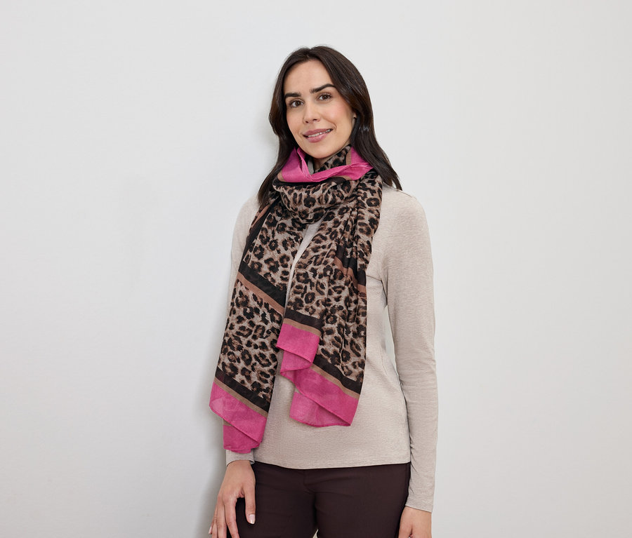 Frau mit dunklem Haar posiert mit einem Schal mit Leopardenmuster und pinkfarbenen Akzenten.