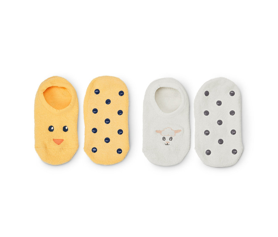 Zwei Paar Hausschuhslippersocken: gelbe mit Gesicht und Punkten, weiße mit Schaf und Punkten.