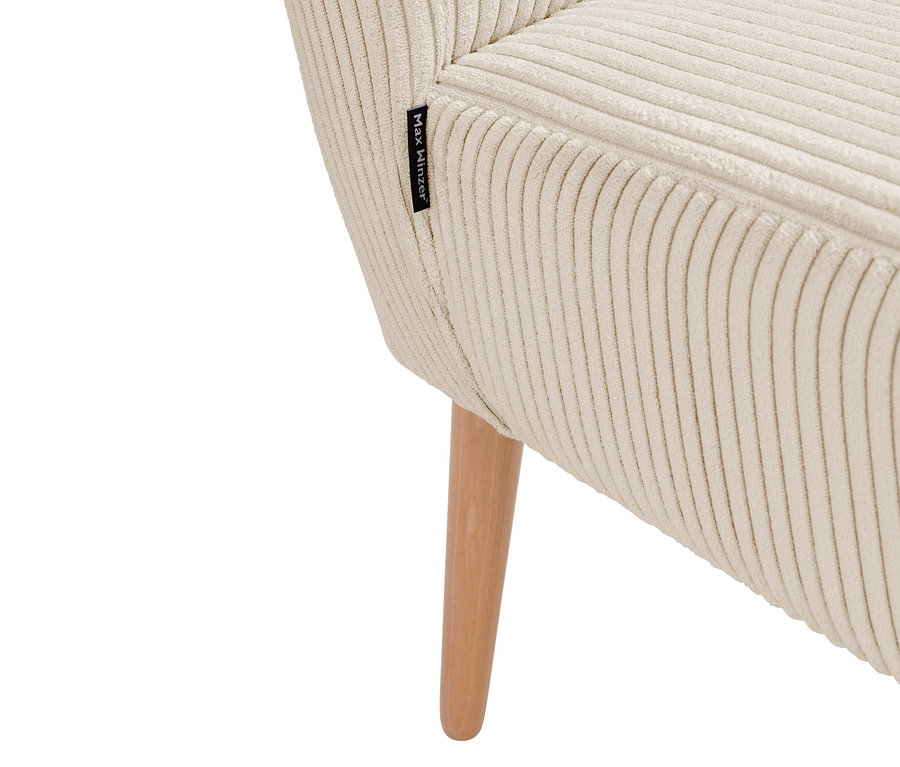 Nahaufnahme einer cremefarbenen Cord-Sitzbank mit Holzbein und einem Etikett der Marke Max Winzer.