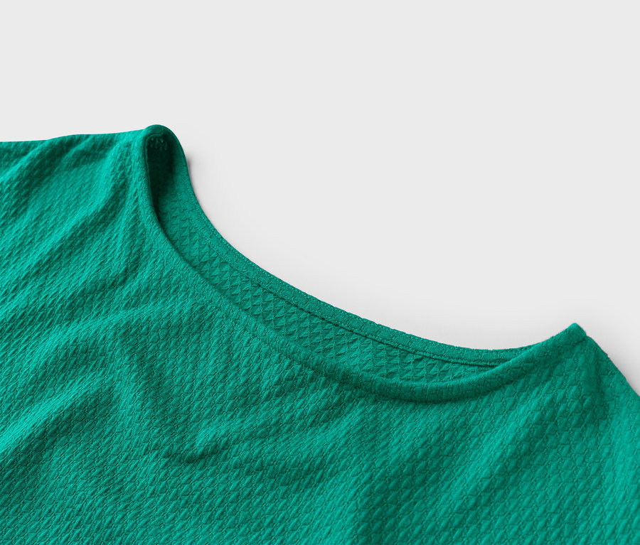 Nahaufnahme eines smaragdgrünen T-Shirts mit Rundhalsausschnitt und Waffelstruktur.