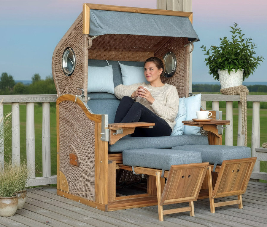 Frau sitzt im DeVries Strandkorb, Akazie, XL mit Kaffeetasse in der Hand.