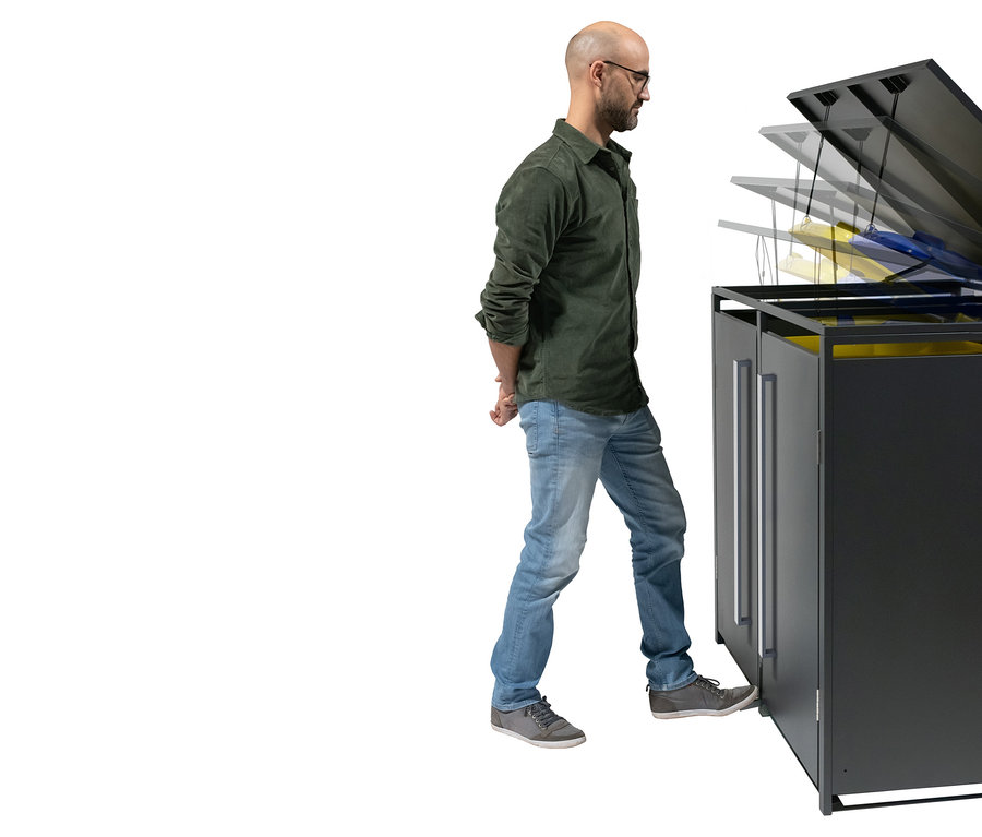 Ein Mann mit Brille öffnet einen schwarzen Mülleimer mit dem Fuß.