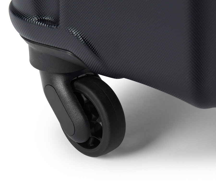 Detailaufnahme eines schwarzen Rollkoffer-Rads auf weißem Untergrund.