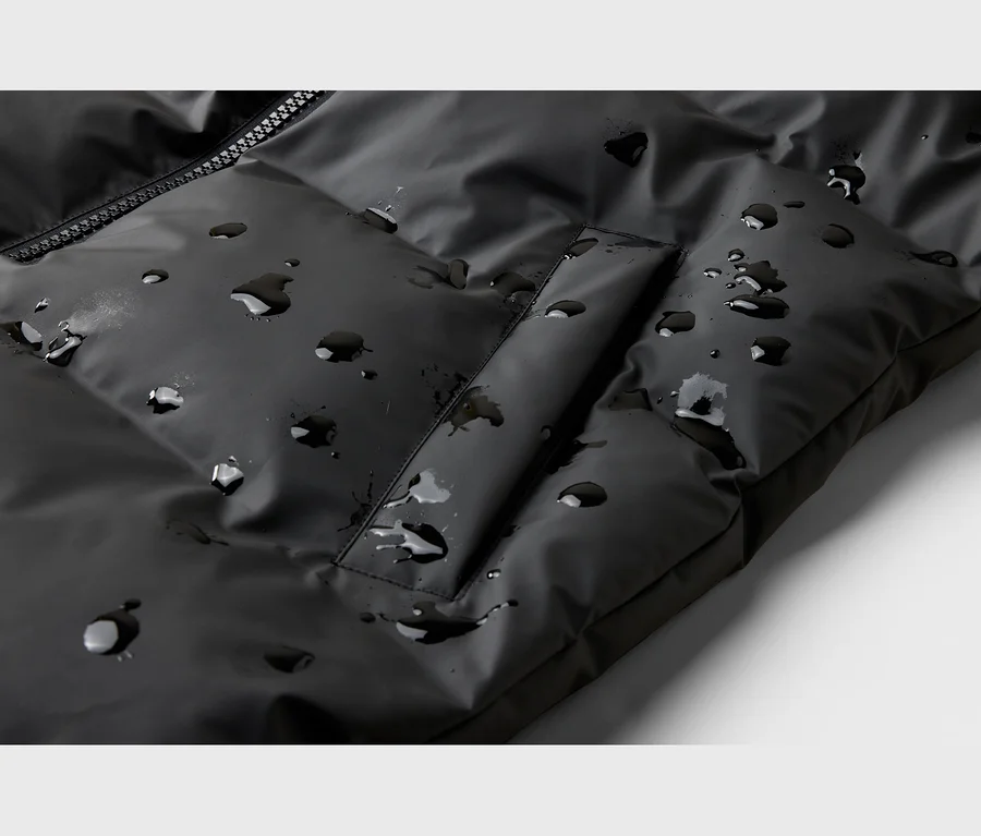 Schwarze, wasserabweisende Steppjacke mit Reißverschluss und Wassertropfen auf der Oberfläche.