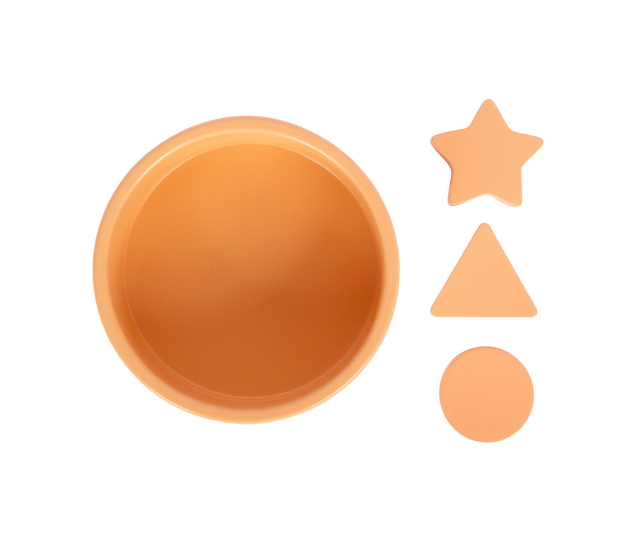 Ein helloranger, runder Behälter und drei hellorange Formen (Stern, Dreieck, Kreis) liegen auf einem weißen Hintergrund. Sie sind Teil des small foot Montessori-Bundle 1.