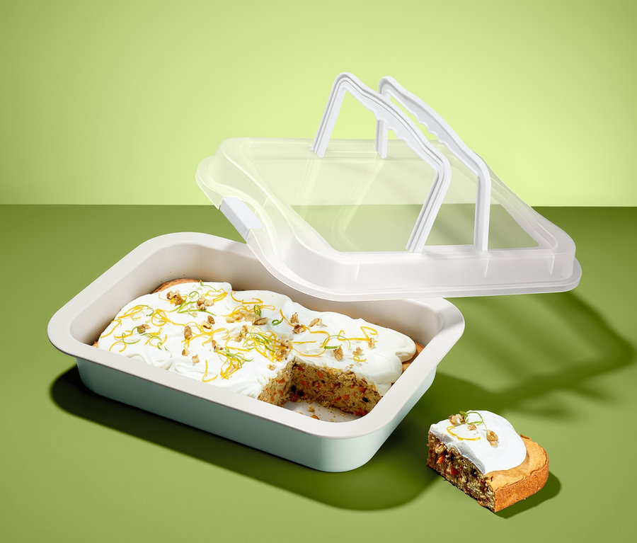 Kuchenstück mit Zuckerguss in Backblech mit Transporthaube.