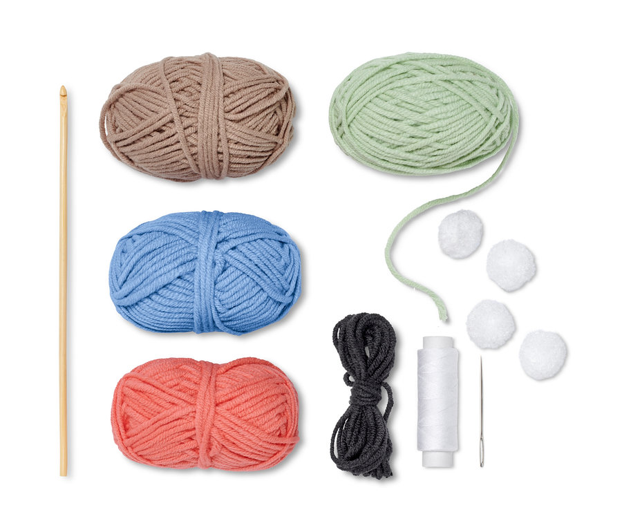 DIY-Häkelset »Eierwärmer« mit braunem, grünem, blauem und korallenrotem Garn, Häkelnadel, Faden, Nadel und Pompons.