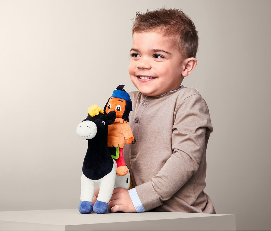 Lächelnder Junge hält Yakari-Plüschtier-Set im Arm.