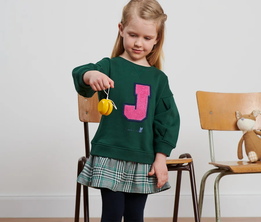 Mädchen hält ein Jojo. Sie trägt ein Kleid.