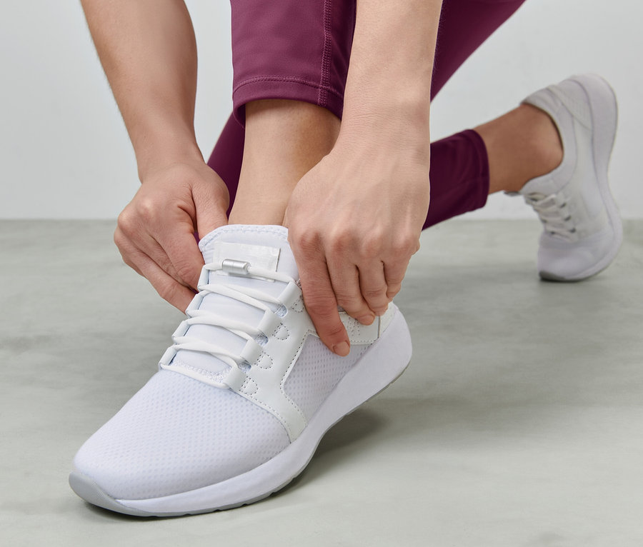 Frau schliesst elastische Schnürsenkel an einem weißen Schuh.