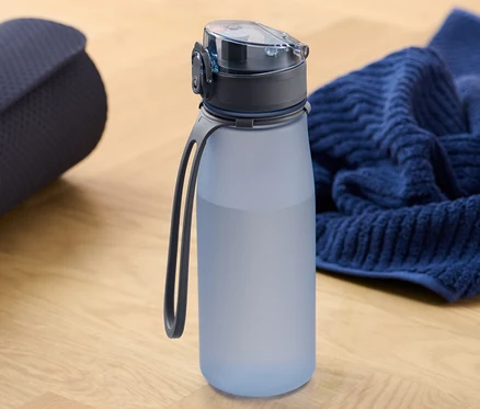 Eine zusammengerollte Yogamatte neben einer Sport-Trinkflasche und einem Handtuch.