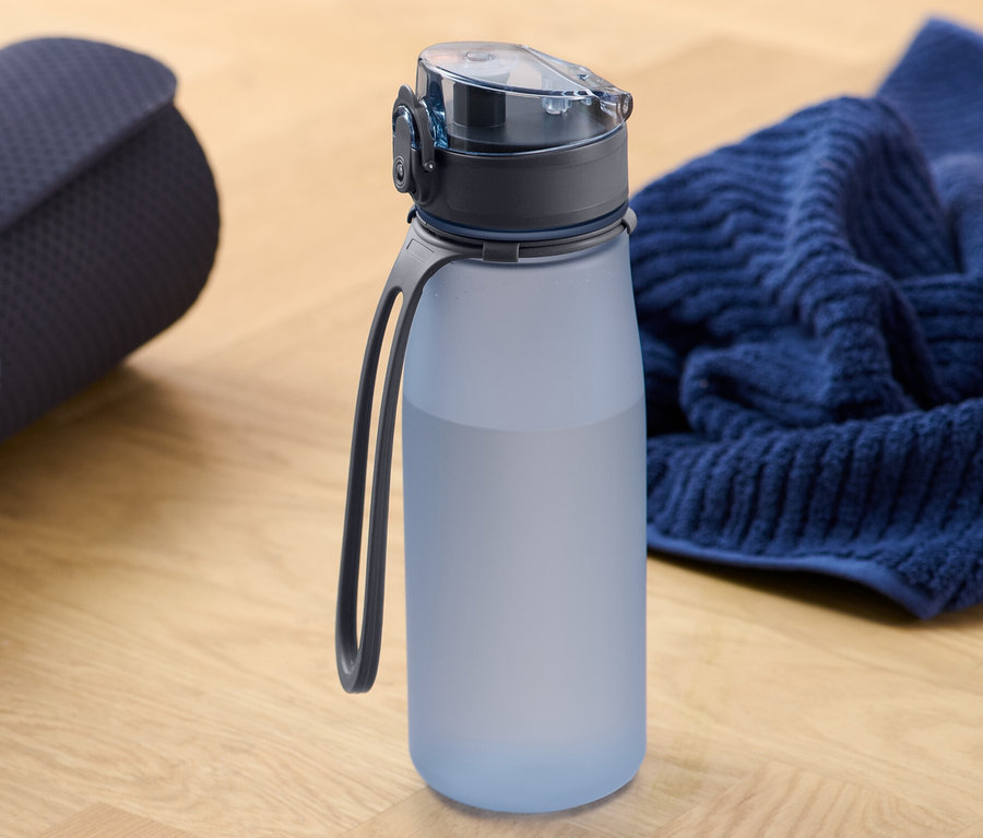 Eine zusammengerollte Yogamatte neben einer Sport-Trinkflasche und einem Handtuch.